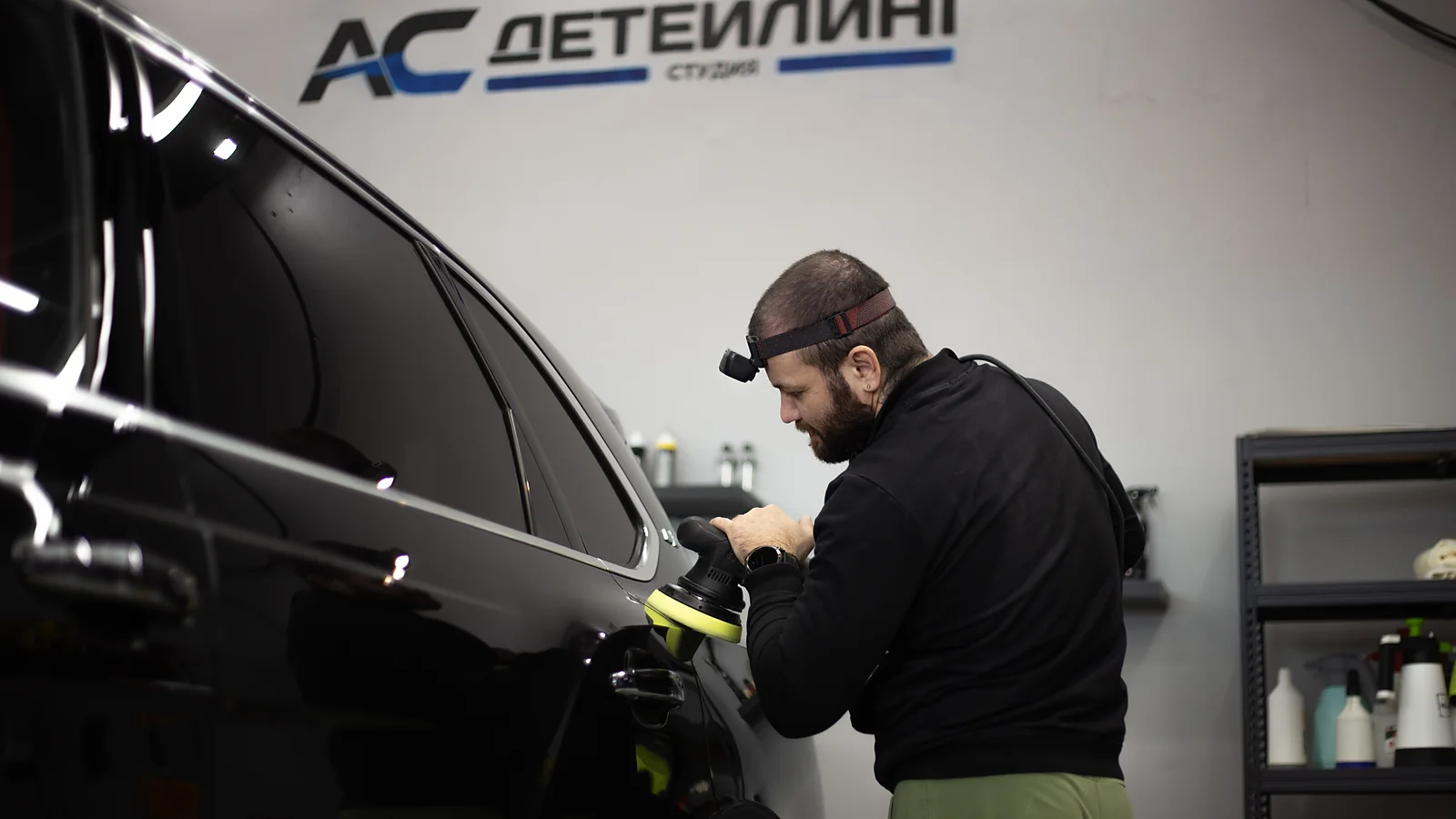 Мастер полирует кузов автомобиля под техническим светом